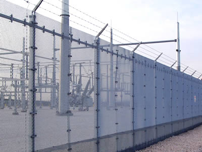 Expanded metal fencing with three lines of barbed wires on topping for power plant security perimeter barrier.