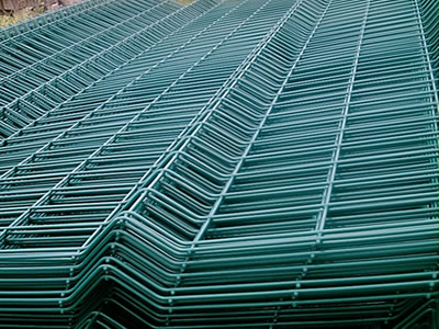 Many green welded panels with V bends piled neatly.