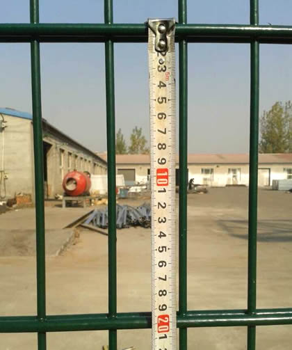 A worker is measuring the hole height of twin wire fence by meter ruler.